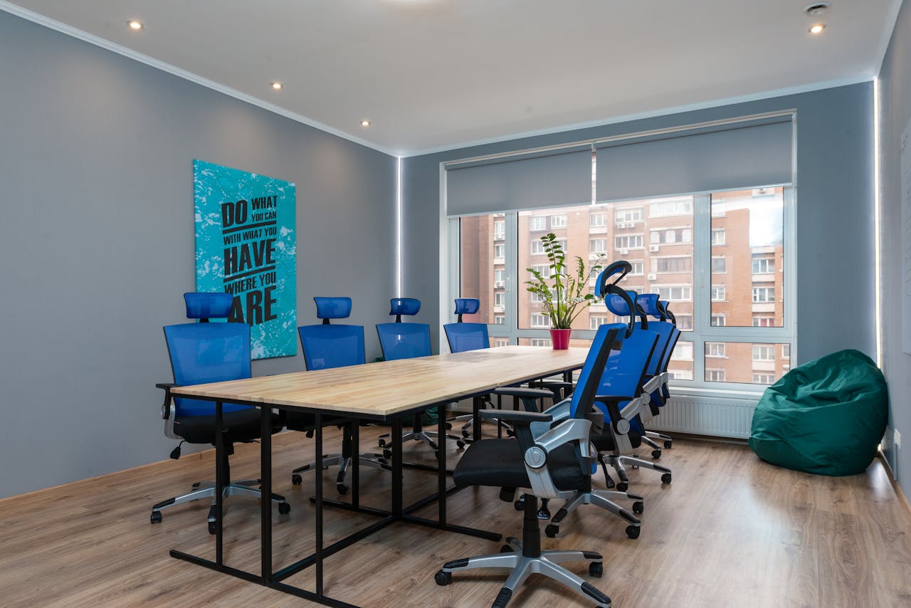 Blue armchairs at wooden table placed in modern conference room with decorative signboard with inscription and window in stylish office building