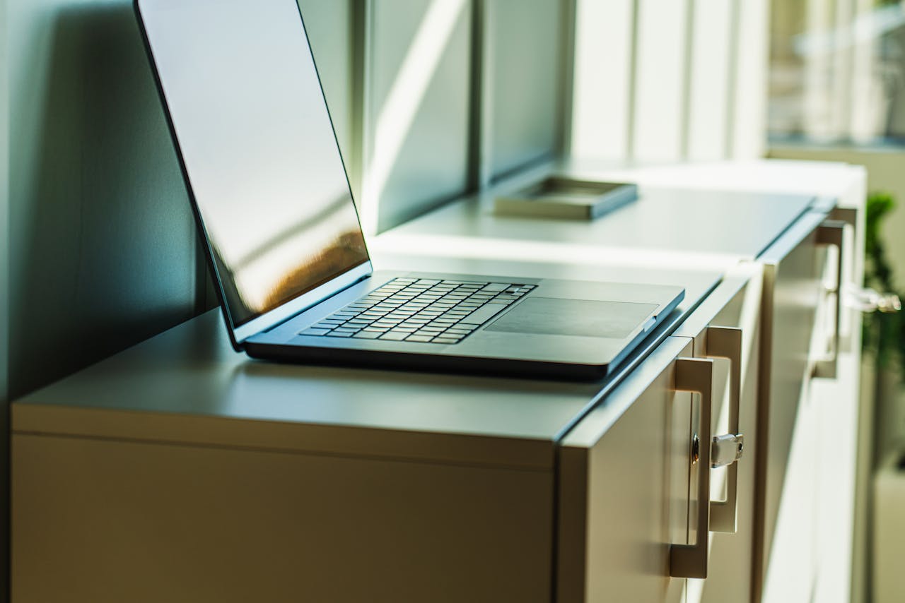 A laptop on a sunlit office cabinet, ideal for professional or corporate contexts.